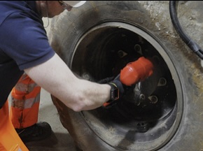 Worker changing a large tire with a power tool